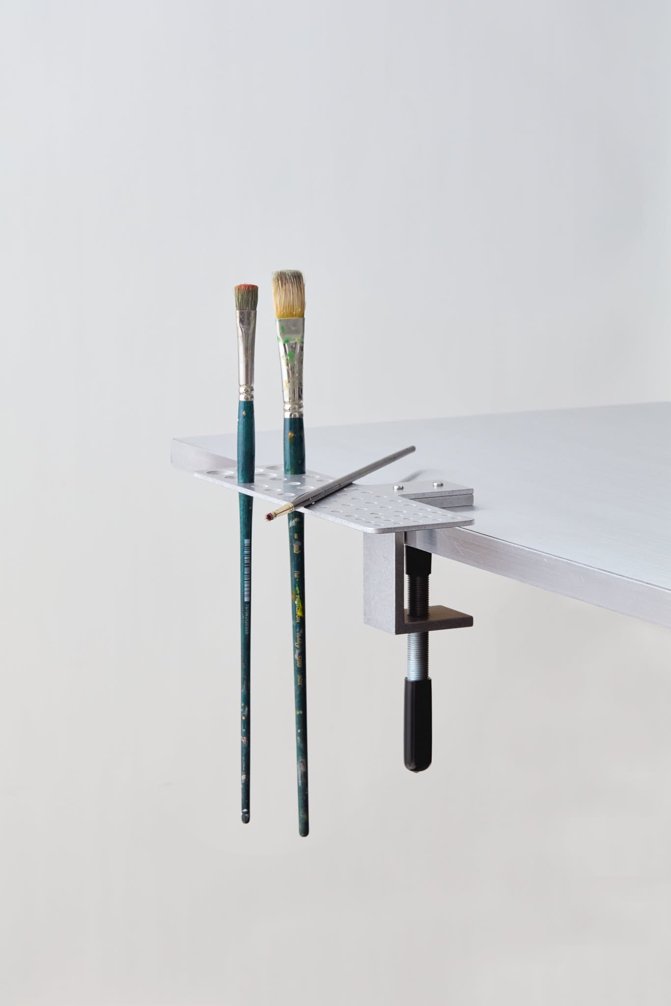 paintbrush holder clamped to the table with brushes