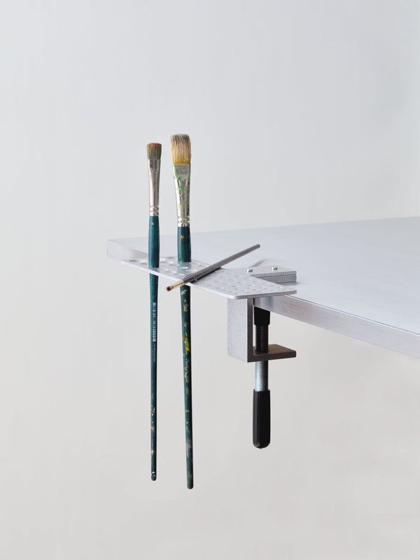 paintbrush holder clamped to the table with brushes